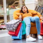Cumparaturi de Craciun, pe locuri, fiti gata: cateva sfaturi pentru a le face cu succes Tired and stressed young woman is lying and resting in the chair with many shopping bags in the mall